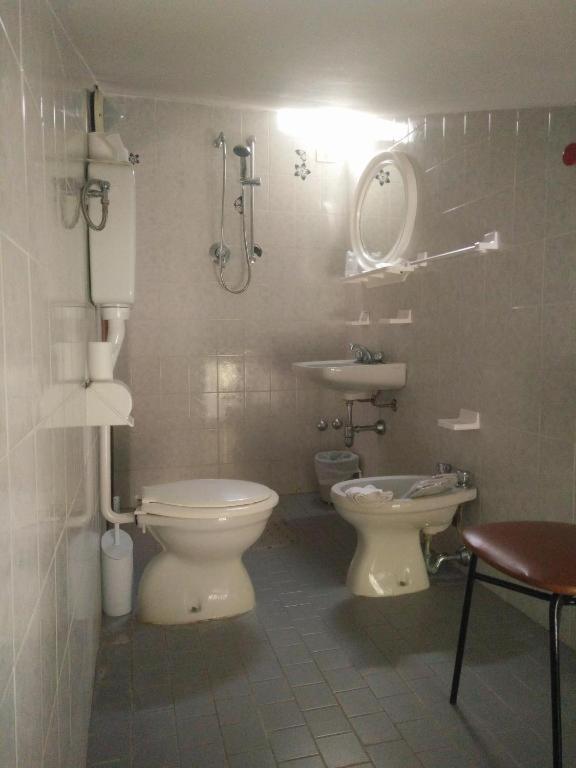 La salle de bains est pourvue de toilettes et d'un lavabo avec miroir. dans l'établissement Hotel Peonia, à Rimini