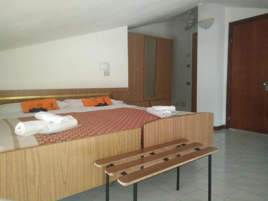 une chambre avec deux lits et un banc en bois dans l'établissement Hotel Peonia, à Rimini