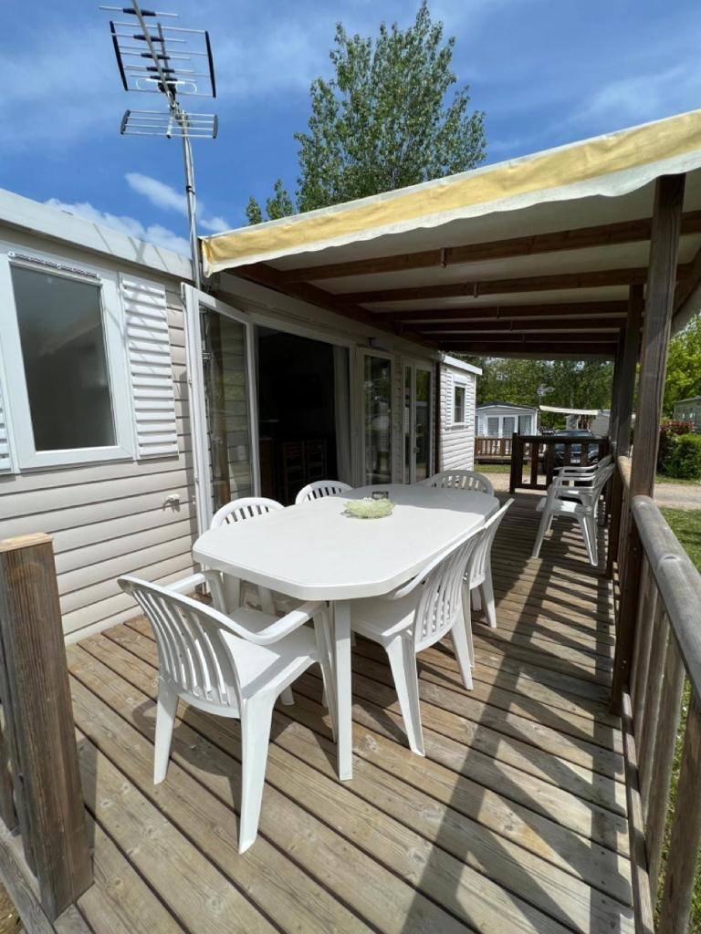 une table et des chaises blanches sur une terrasse en bois dans l'établissement Mobil-Home 4 étoiles avec piscine proche de Blois, à Onzain