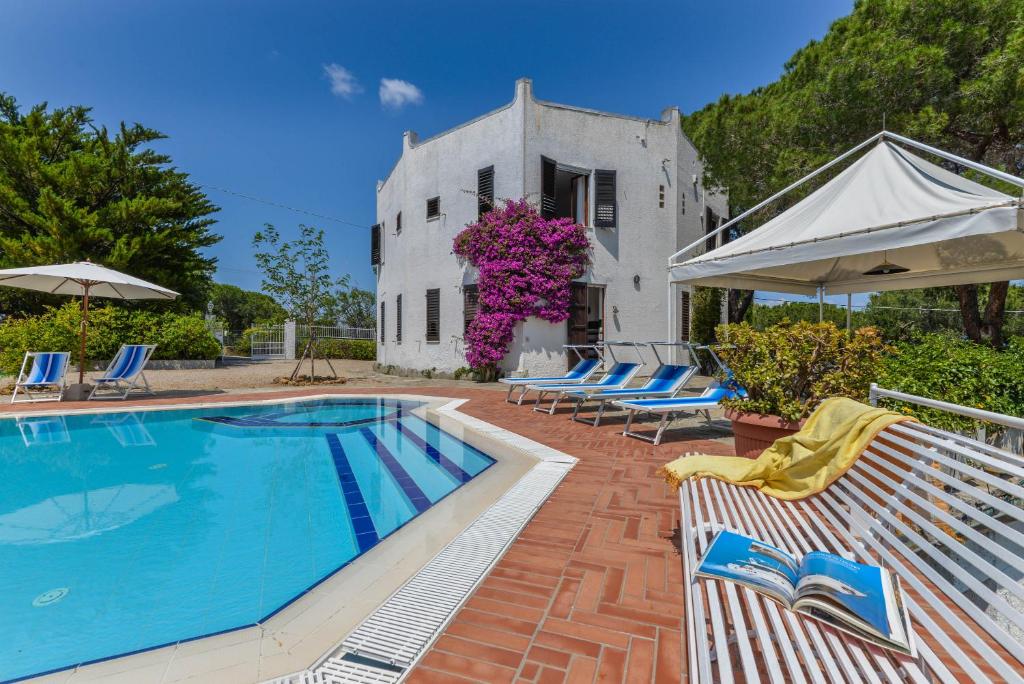 une piscine en face d'une maison avec des chaises et d'un bâtiment dans l'établissement Villa Ottagonale, à Capoliveri