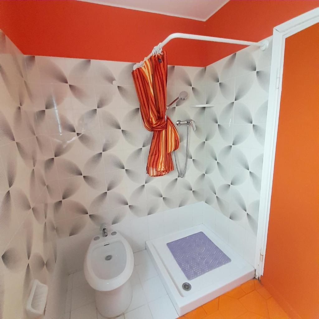 La salle de bains est pourvue de toilettes et d'un rideau de douche orange. dans l'établissement Hotel Maddalena, à Marina di Ravenna 48 autres photos