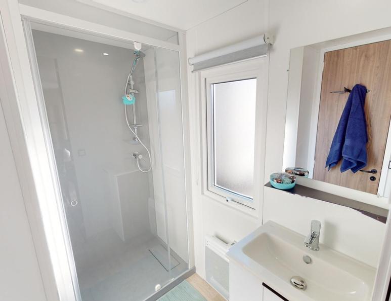 une salle de bain blanche avec une douche et un lavabo dans l'établissement Mobil home 4/6 personnes, à Seignosse