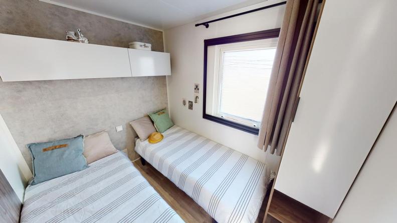 une petite chambre avec deux lits et une fenêtre dans l'établissement Mobil home 4/6 personnes, à Seignosse