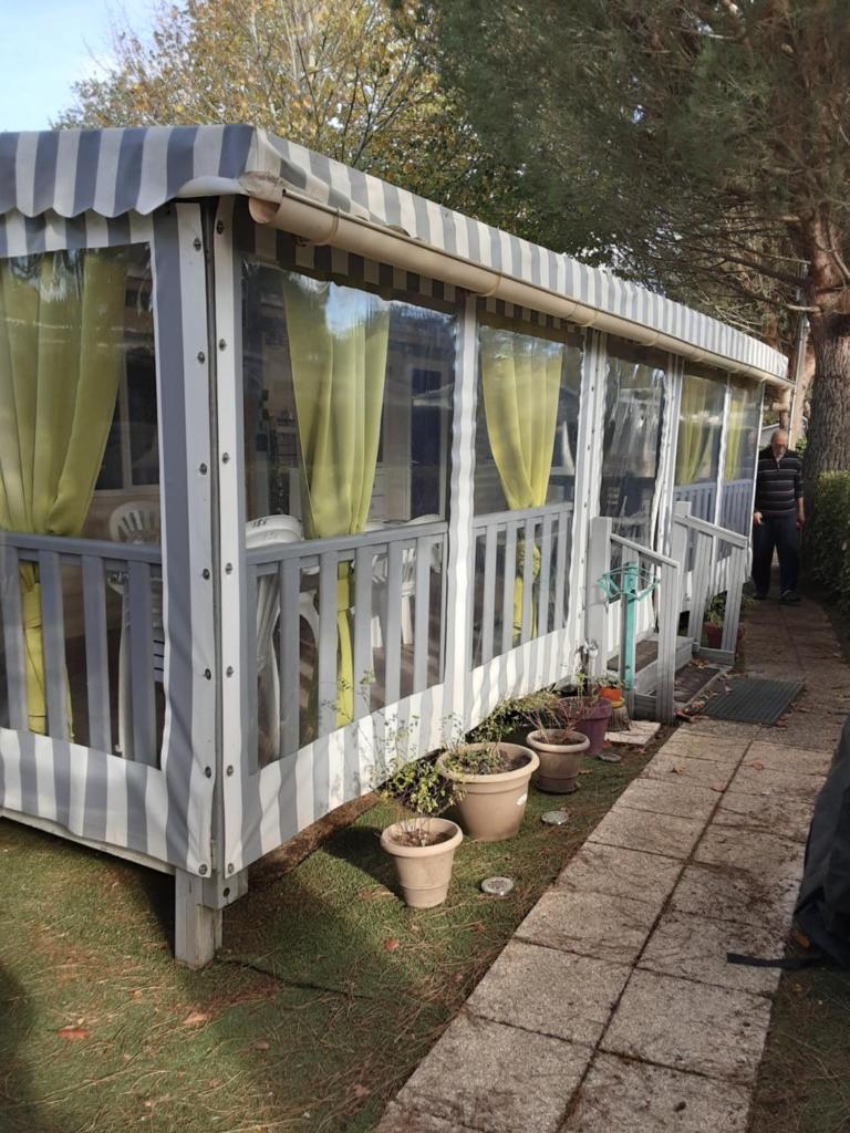 un kiosque blanc avec des rideaux jaunes et des plantes en pot dans l'établissement mobil home tout équipé 3 chambres, à Gastes