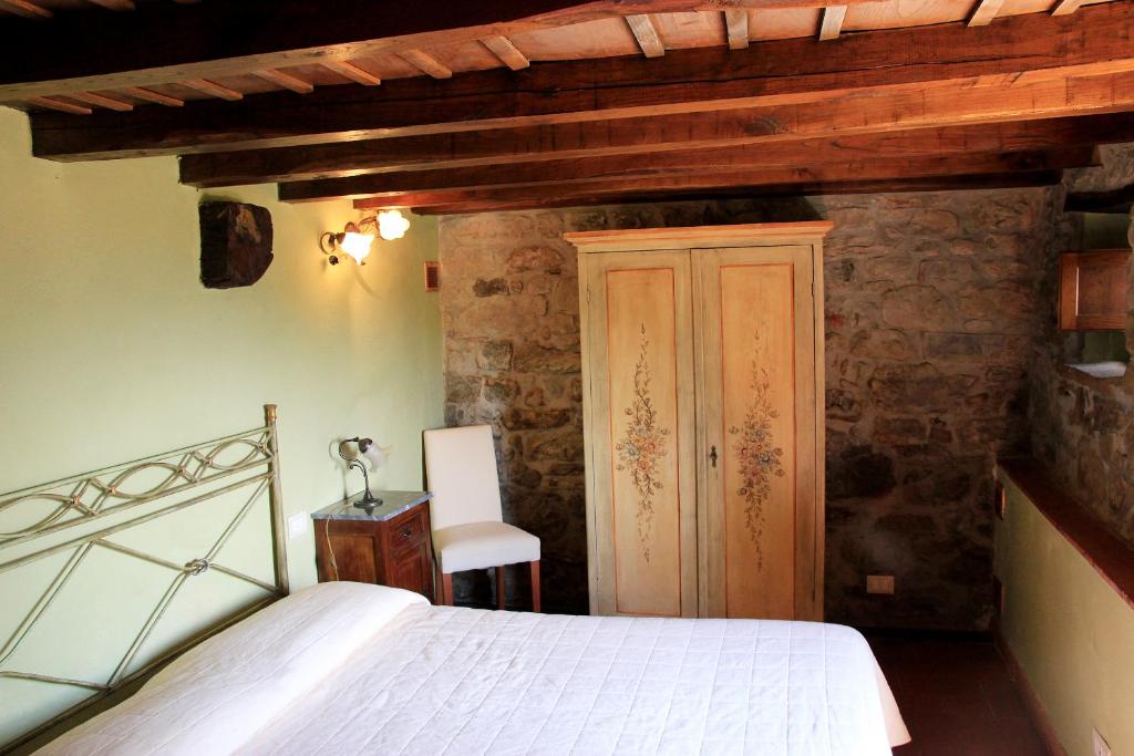 une chambre avec un lit blanc et une chaise dans l'établissement Tuscany Villa Chianti Hills - Villa Oliveta, à Loro Ciuffenna