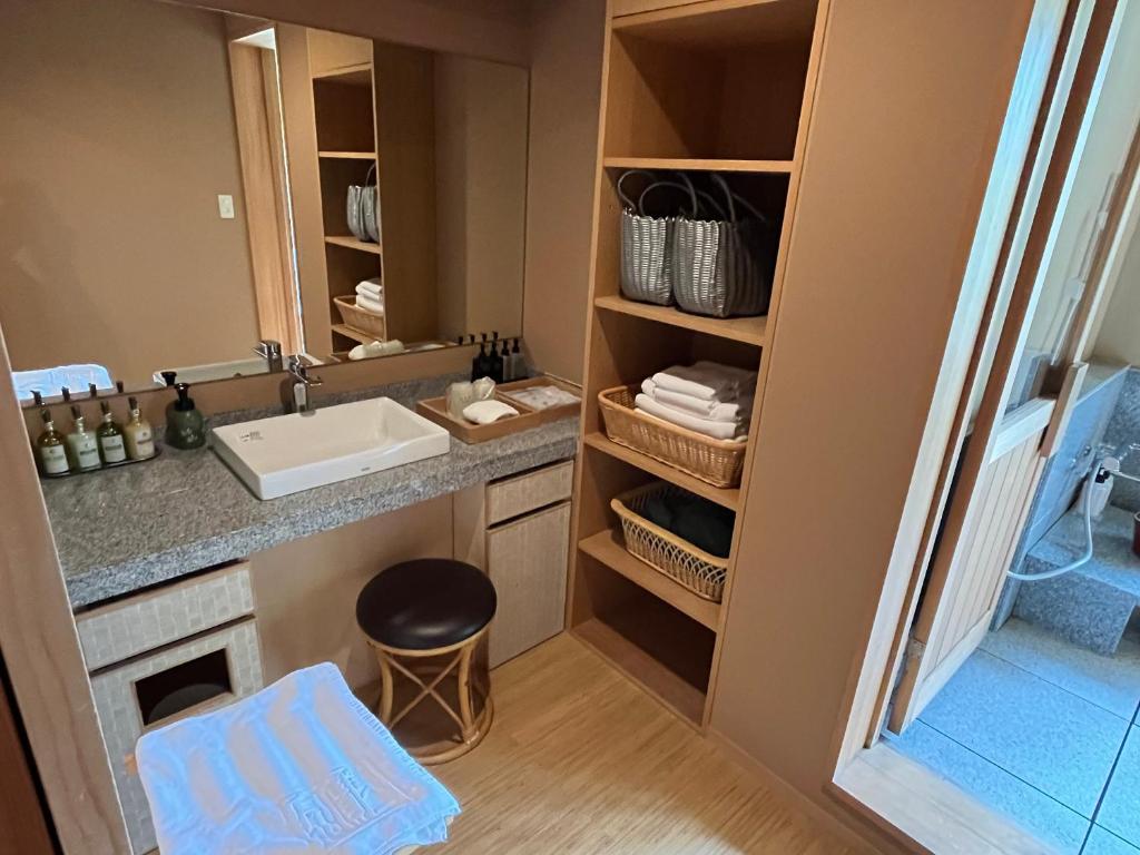 une salle de bain avec un lavabo et un comptoir avec un tabouret dans l'établissement Jozankei Daiichi Hotel Suizantei, à Jozankei