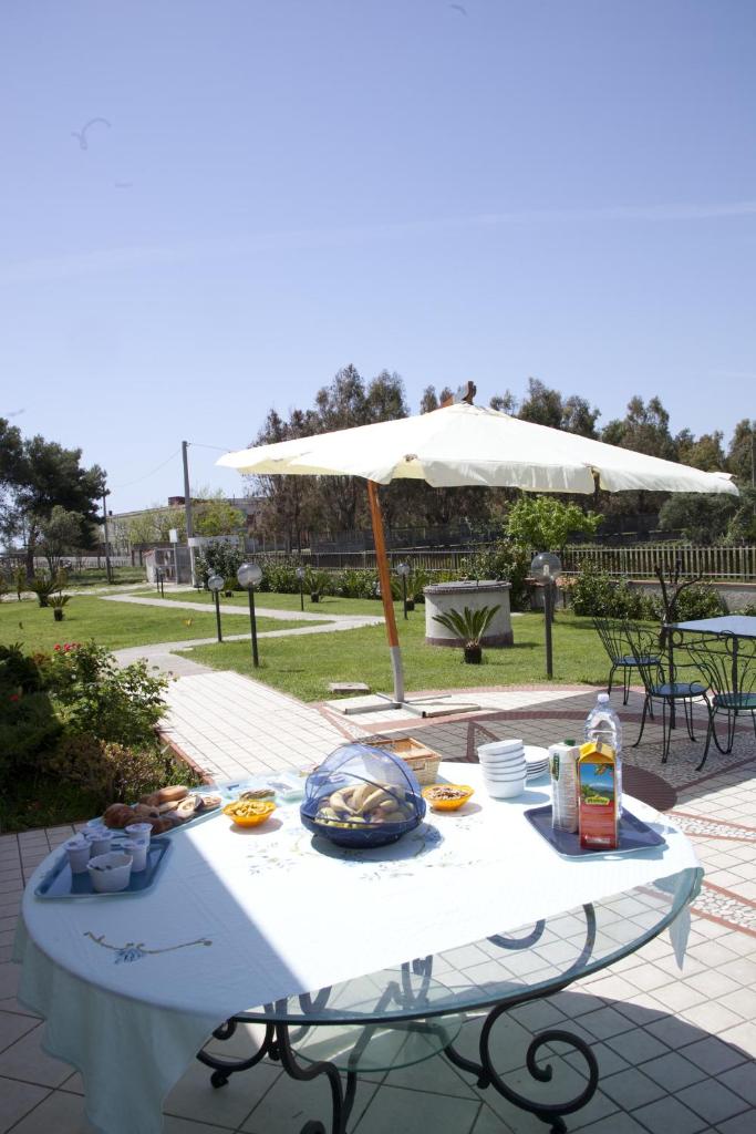 - une table blanche avec de la nourriture et un parasol dans l'établissement Villa Maredona, à Ascea