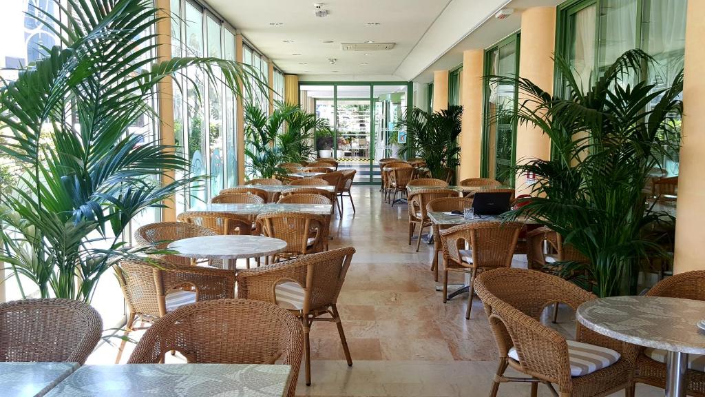 un restaurant avec des tables, des chaises et des plantes dans l'établissement Hotel Poker, à Riccione