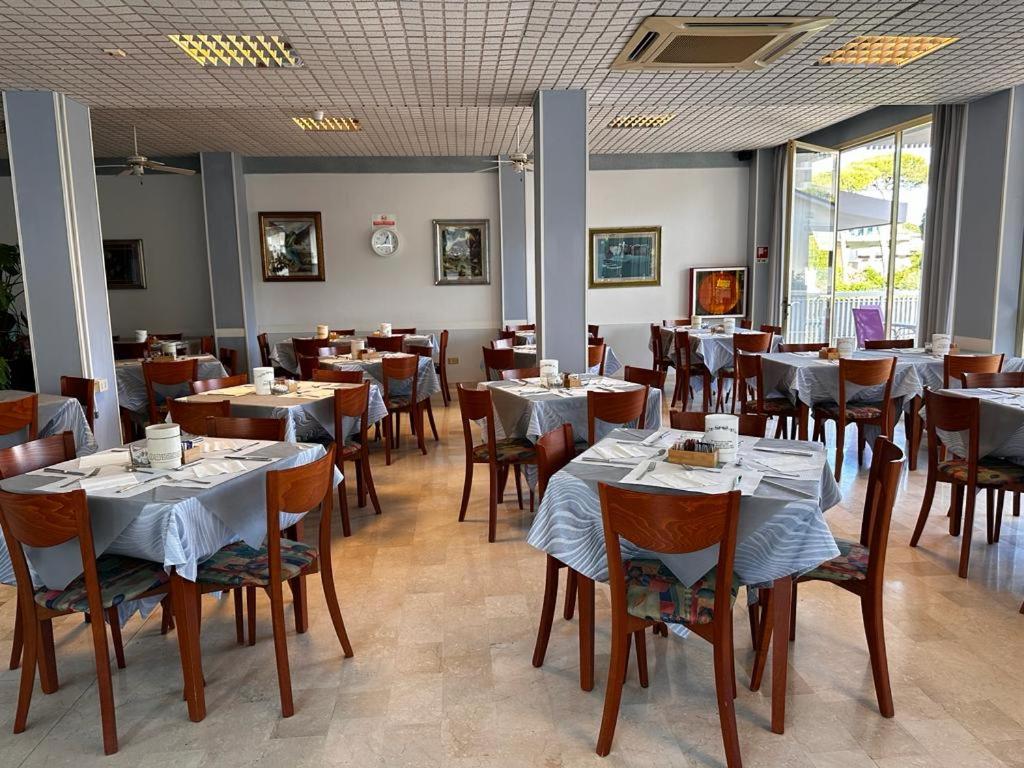 une salle à manger avec des tables et des chaises dans un restaurant dans l'établissement Hotel Singapore, à Milano Marittima