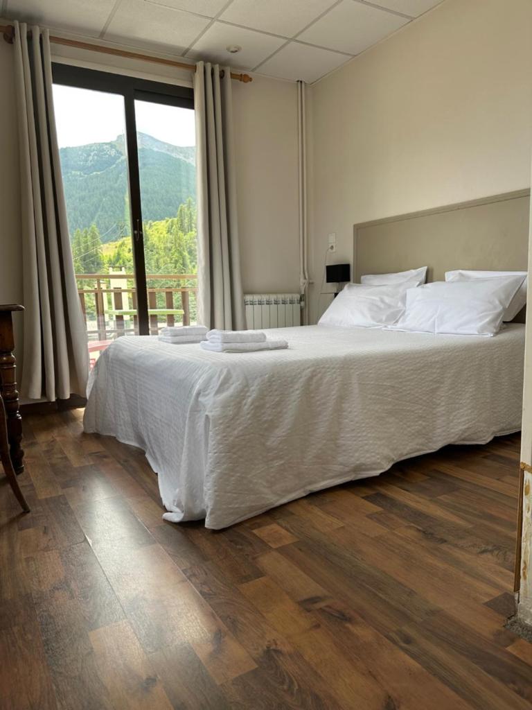 une chambre avec un grand lit et une grande fenêtre dans l'établissement Hotel Edelweiss, à Auron