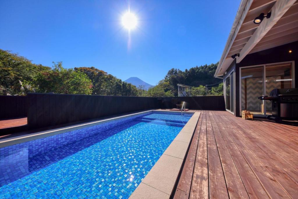 une piscine avec une terrasse en bois à côté d'une maison dans l'établissement グランド―ム　富士忍野, à Minamitsuru