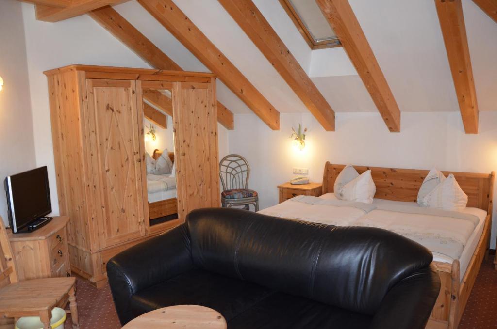 - une chambre avec un lit et un canapé en cuir dans l'établissement Alpenlandhotel Rodeneggerhof, à Rodengo