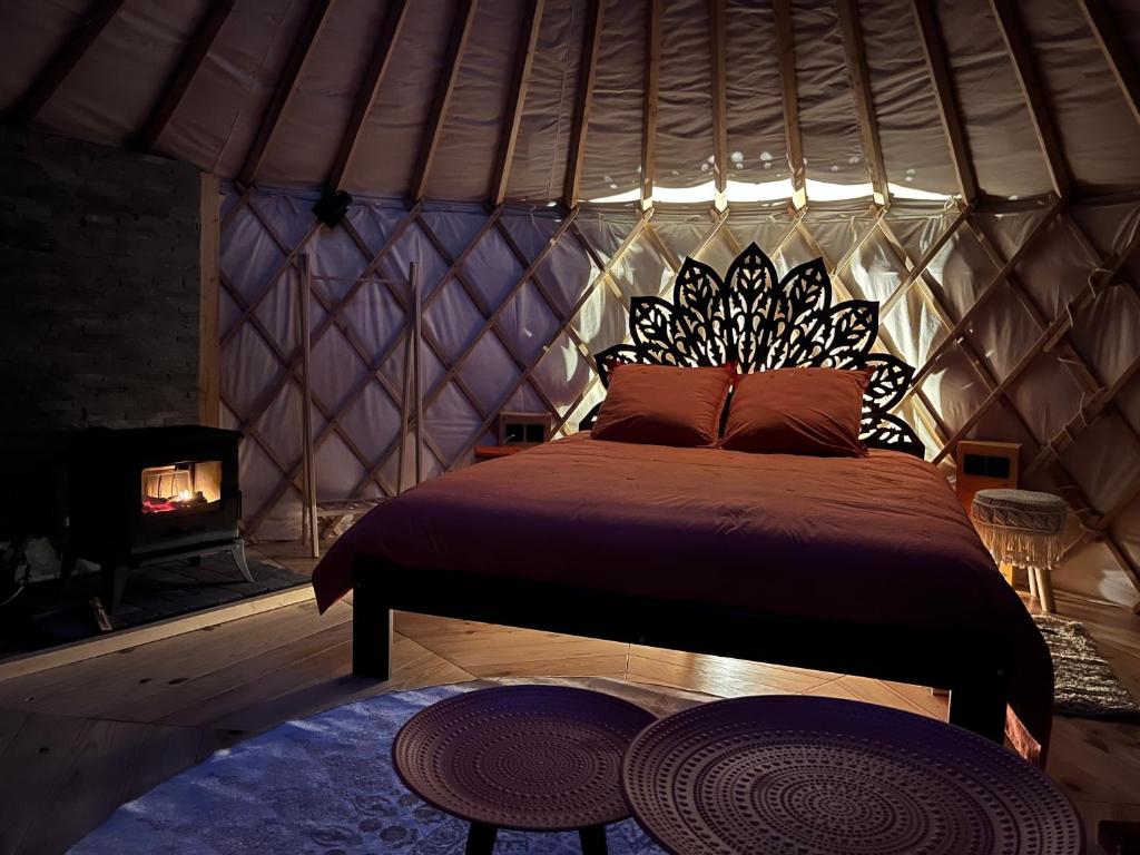 une chambre avec un lit dans une yourte avec cheminée dans l'établissement Aux Étangs de Jourgnac - Yourte, à Jourgnac