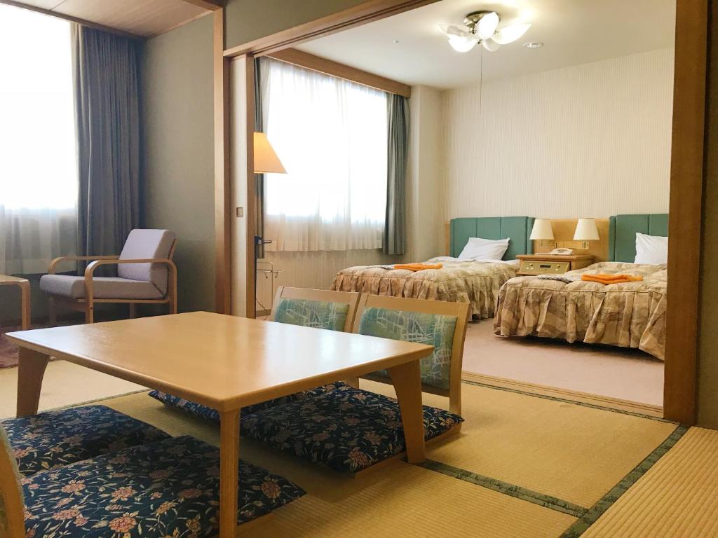 une chambre d'hôtel avec une table et deux lits dans l'établissement Hotel Tetoraresort Tokachigawa, à Otofuke