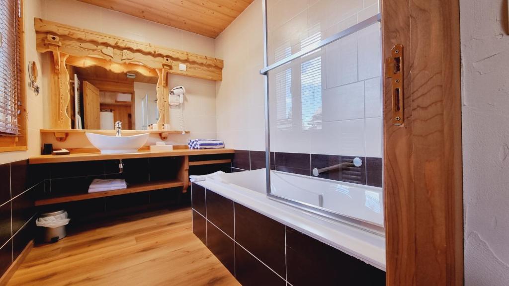 La salle de bains est pourvue d'une grande baignoire et d'un lavabo. dans l'établissement Hôtel Le Sporting, à Morzine