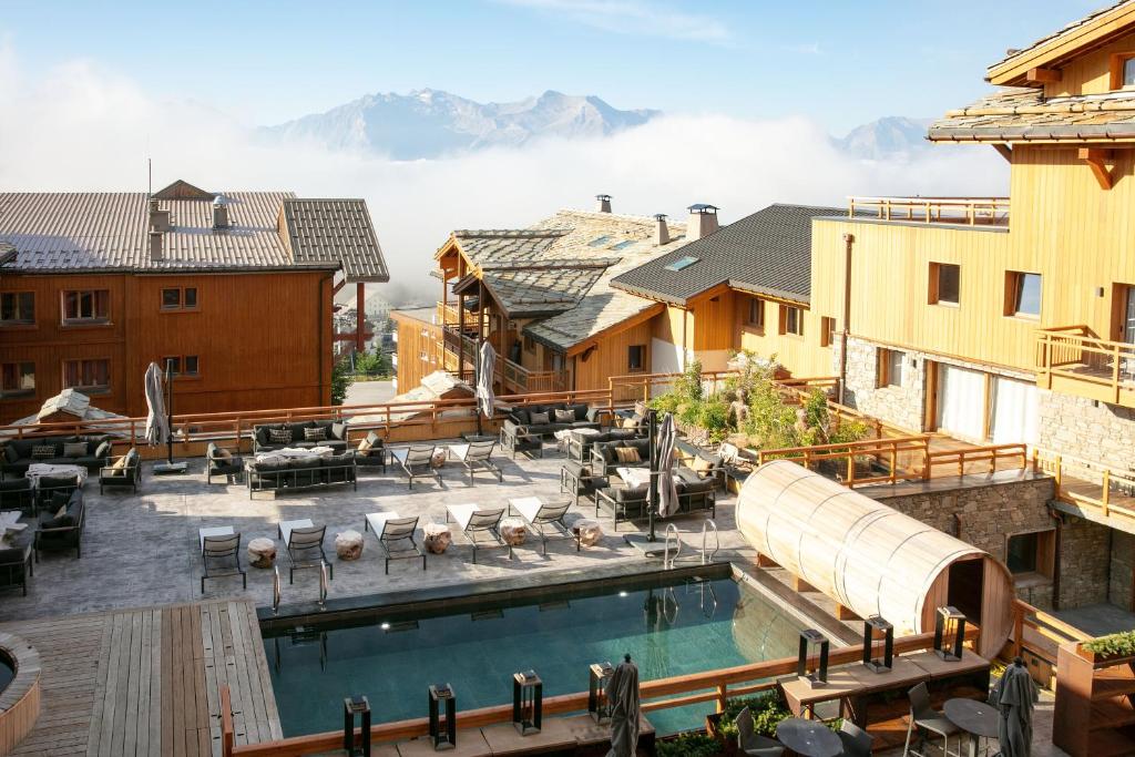 une piscine au-dessus d'un bâtiment avec des montagnes en arrière-plan dans l'établissement Grandes Rousses Hotel & Spa, à L'Alpe-d'Huez