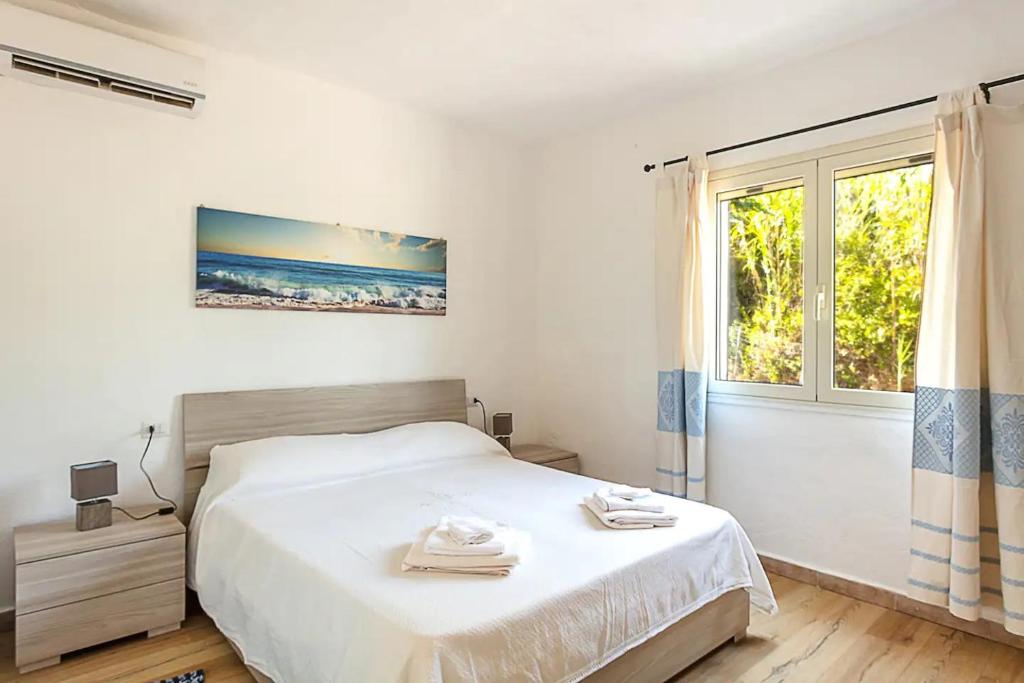 une chambre blanche avec un lit et une fenêtre dans l'établissement Villa Lara, à Cugnana