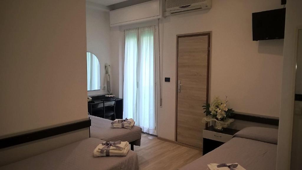 une chambre d'hôtel avec deux lits et un miroir dans l'établissement Hotel Tre Stelle, à Rimini
