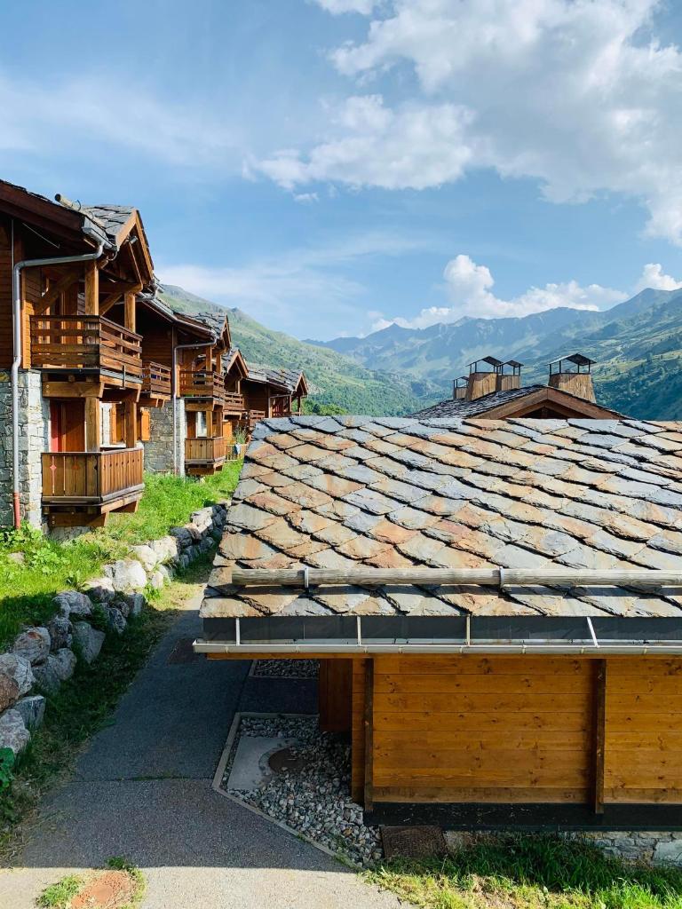 le toit d'un bâtiment avec des montagnes en arrière-plan dans l'établissement Cosy Montagne, à Valmeinier