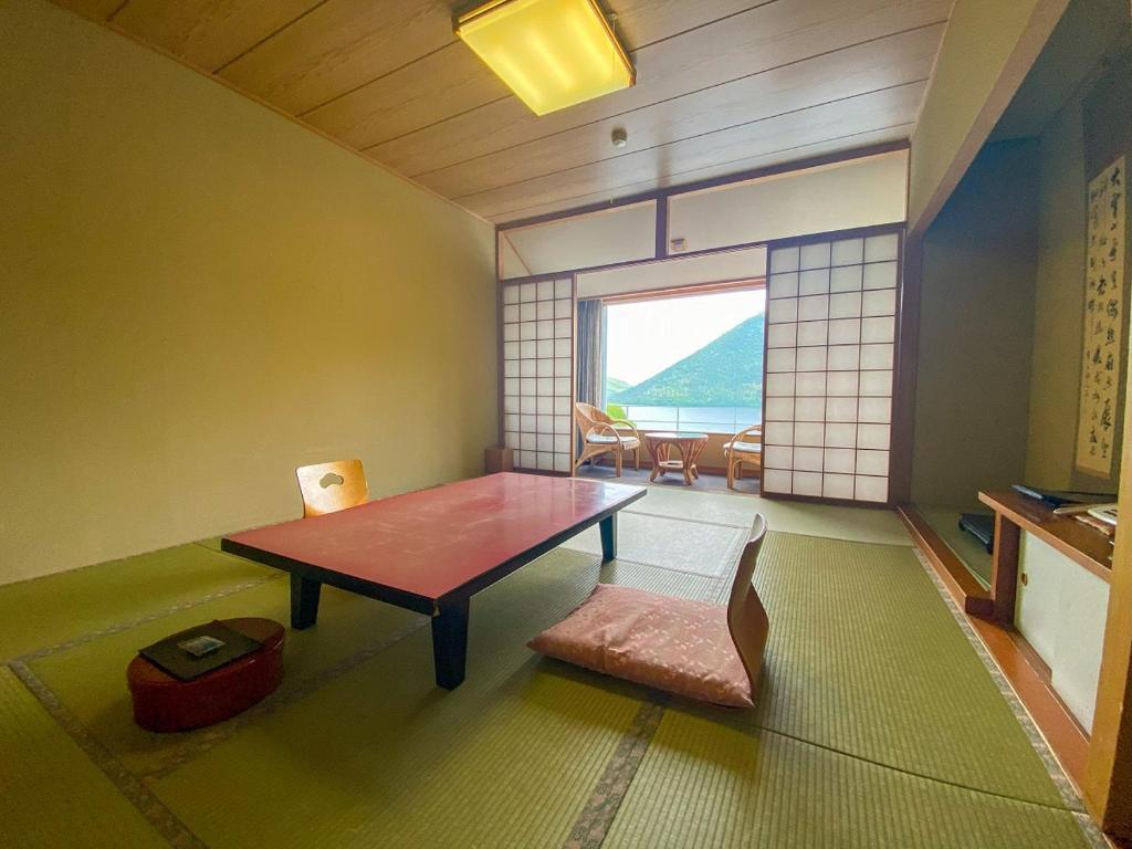 une pièce avec une table, une chaise et une fenêtre dans l'établissement Shikaribetsu Kohan Onsen Hotel Fusui, à Shikaoi