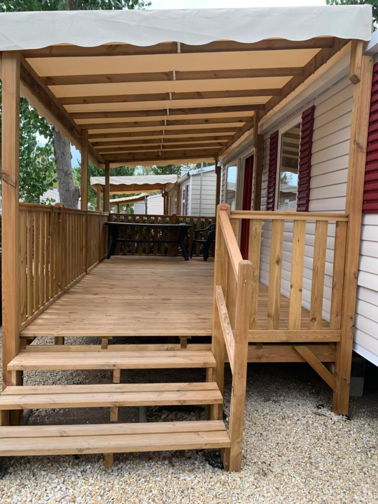 une terrasse en bois avec un auvent sur une maison dans l'établissement les sables du midi, à Valras-Plage
