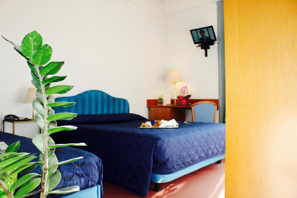 une chambre avec un lit bleu et une plante dans l'établissement Arcangelo Roof Hotel, à Rimini