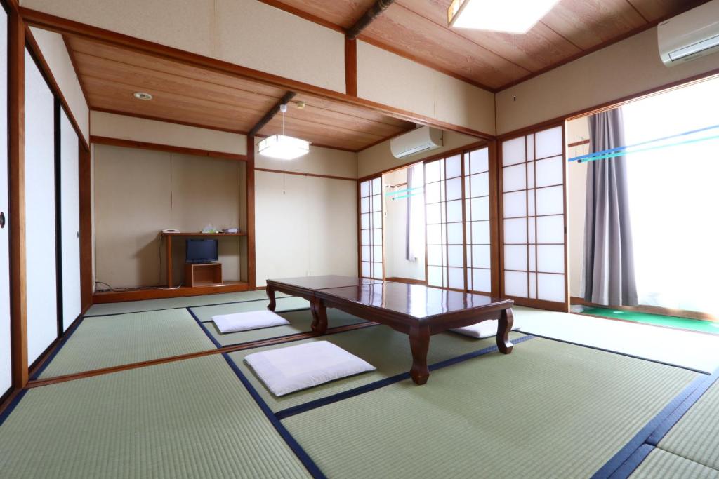 une pièce avec une table dans une pièce avec des fenêtres dans l'établissement Suikoen, à Yonago