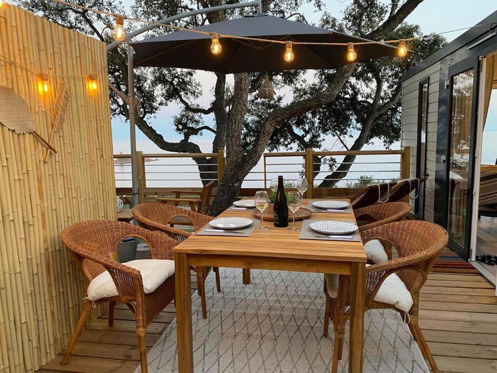 une table en bois avec des chaises et un parasol sur une terrasse dans l'établissement L'arbre perché, à Saint-Raphaël