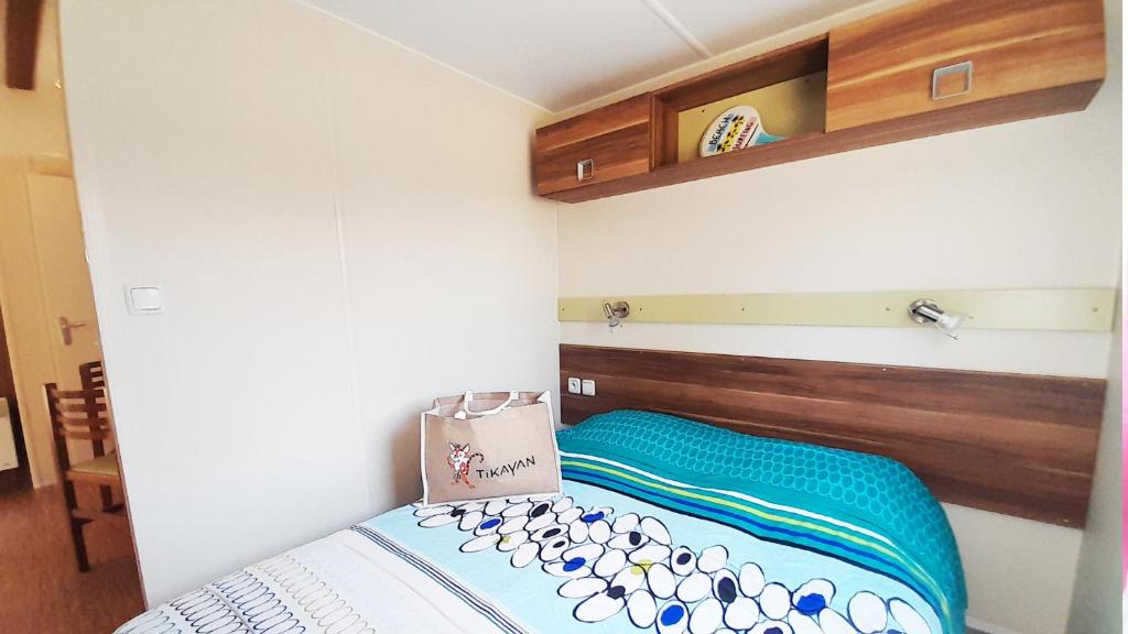 - une petite chambre avec un lit et une couverture bleue dans l'établissement Camping Tikayan La Célestine, à Beynes