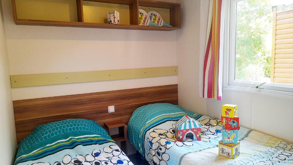 Cette chambre pour enfants comprend 2 lits et une fenêtre. dans l'établissement Camping Tikayan La Célestine, à Beynes