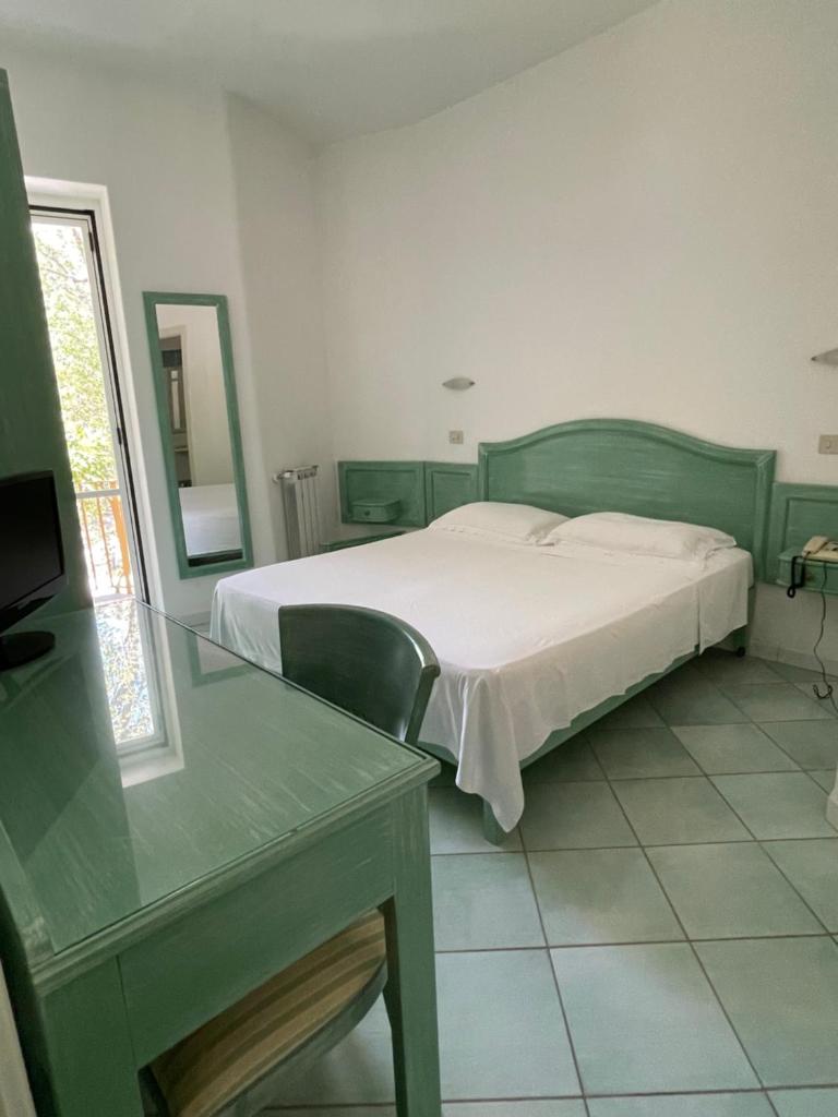 une chambre avec un lit et une table en verre dans l'établissement Albergo Olmitello - cucina vegetariana bio e tradizionale, à Ischia