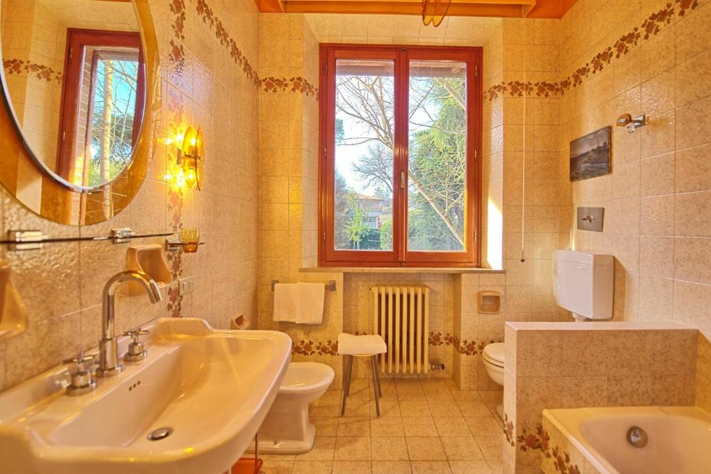 une salle de bain avec un lavabo, des toilettes et un miroir dans l'établissement Villa Lauretana by PosarelliVillas, à Torrita di Siena