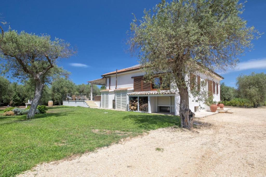 une maison avec deux arbres devant elle dans l'établissement Villa Olivetta con piscina, à Alghero