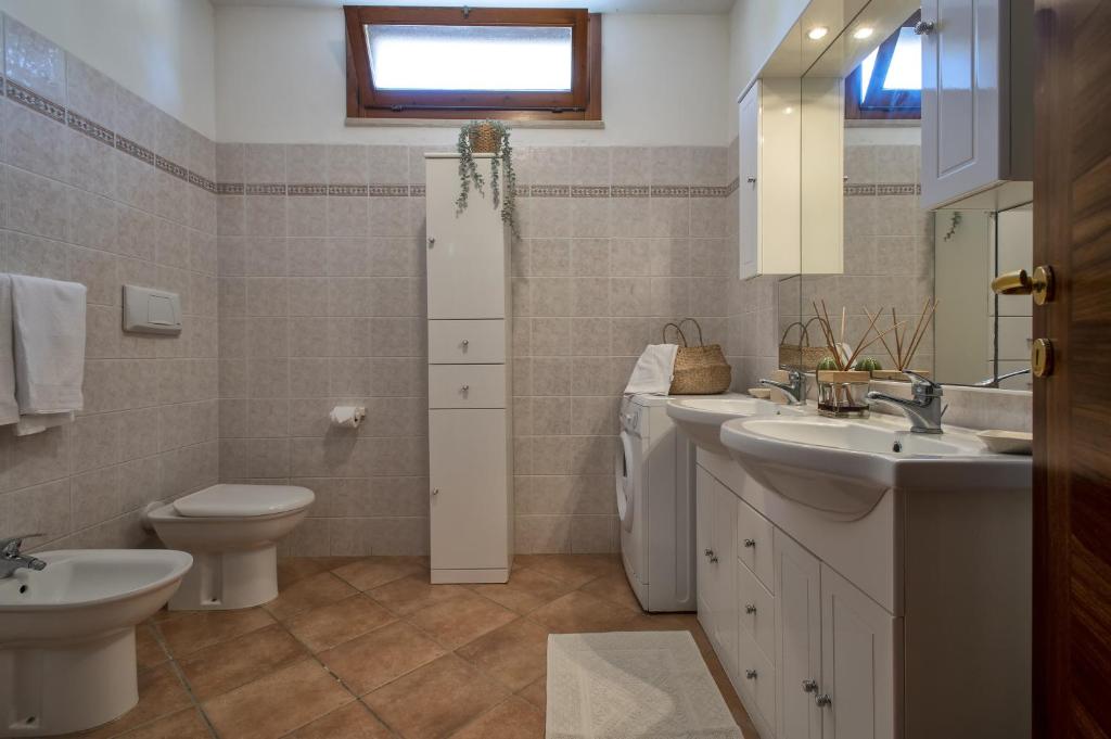 une salle de bain avec deux lavabos et un WC dans l'établissement Villa Olivetta con piscina, à Alghero