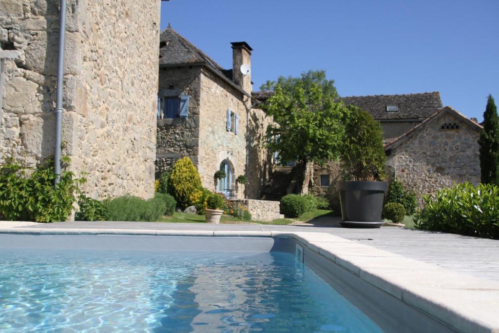 une piscine devant un bâtiment en pierre dans l'établissement La Maison d'Emile- le Gîte- La Clef de la Grange, à La Fouillade