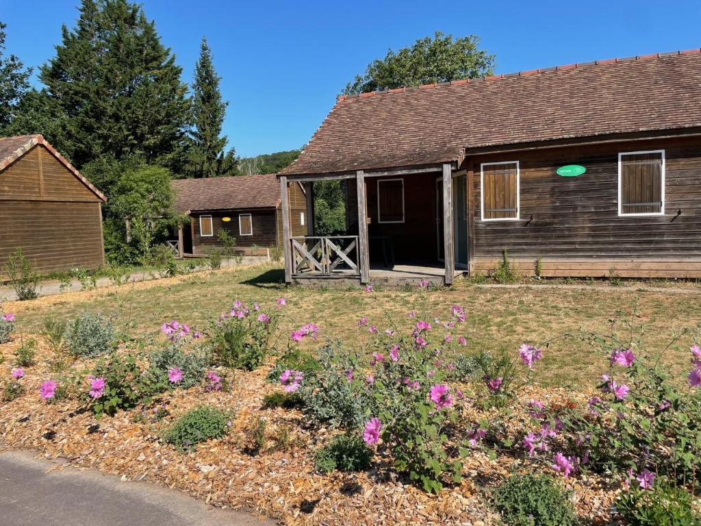 une maison avec une cour fleurie devant elle dans l'établissement Camping Onlycamp Le Pont Romain, à Yvré-lʼÉvêque