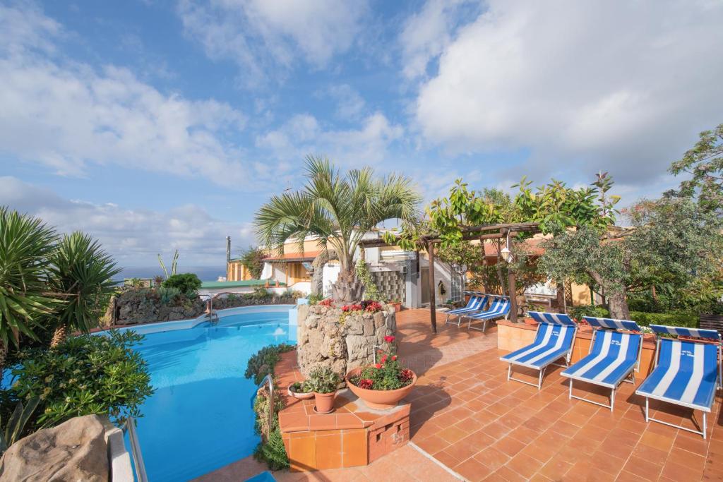 une terrasse avec des chaises bleues et une piscine dans l'établissement Hotel Villa Sirena, à Ischia