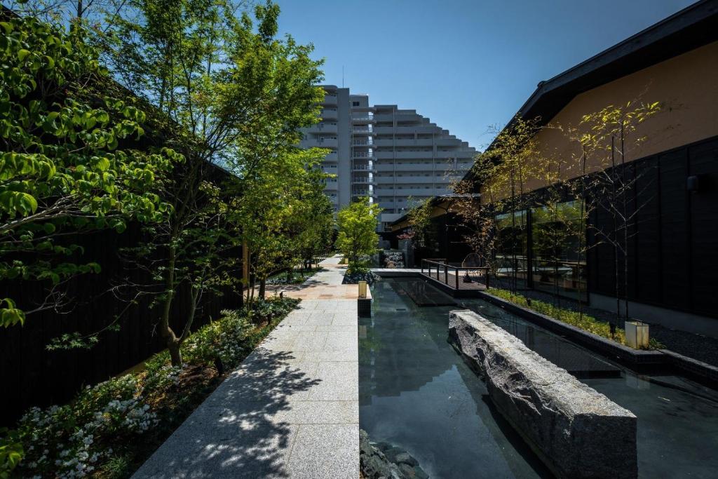 une passerelle entre deux bâtiments avec un bassin d'eau dans l'établissement HOSHINO-OTOー星音, à Miyazu