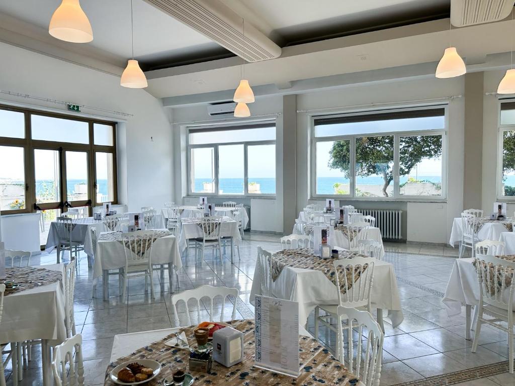 un restaurant avec des tables et des chaises blanches et des fenêtres dans l'établissement Villa MG Hotel, à Santa Marinella