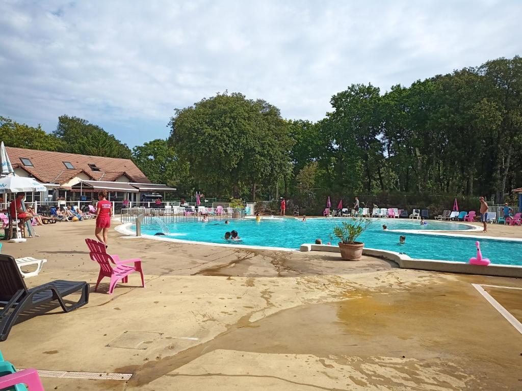une piscine avec des chaises et des gens dans l'eau dans l'établissement Mobil-home tout confort à 300m de l'océan, à Saint-Brévin-les-Pins