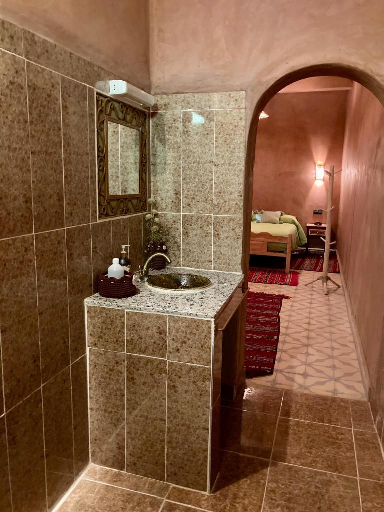 une salle de bain avec un lavabo et une chambre avec un lit dans l'établissement Riad Imuhar, à M'Hamid El Ghizlane