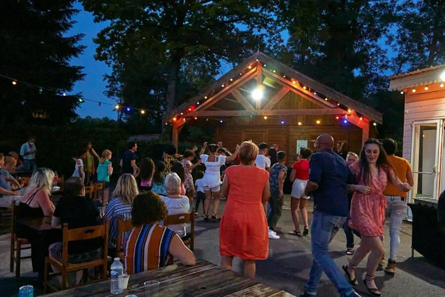 un groupe de personnes debout à l'extérieur d'un bâtiment dans l'établissement Ghislain et Pat, à Saint-Chéron