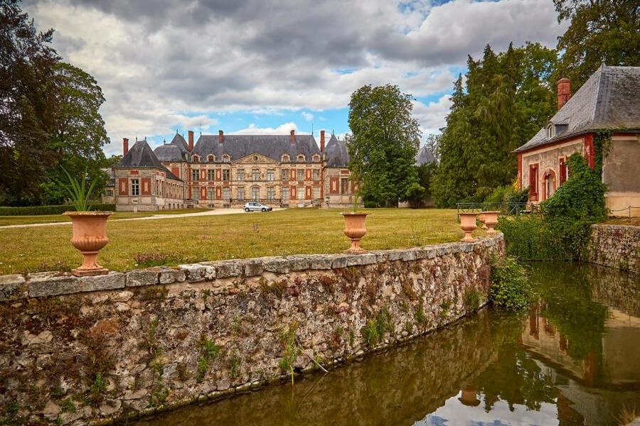 un mur de pierre devant un grand château dans l'établissement Ghislain et Pat, à Saint-Chéron