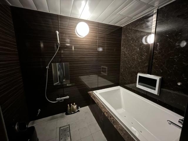 La salle de bains est pourvue d'une grande baignoire et d'une douche. dans l'établissement ホテル ジェムジェム 十三, à Osaka