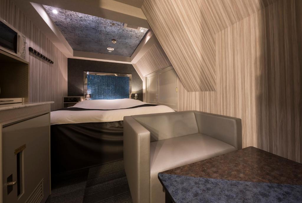 une petite pièce avec un lit et une chaise dans l'établissement ホテル ジェムジェム 十三, à Osaka