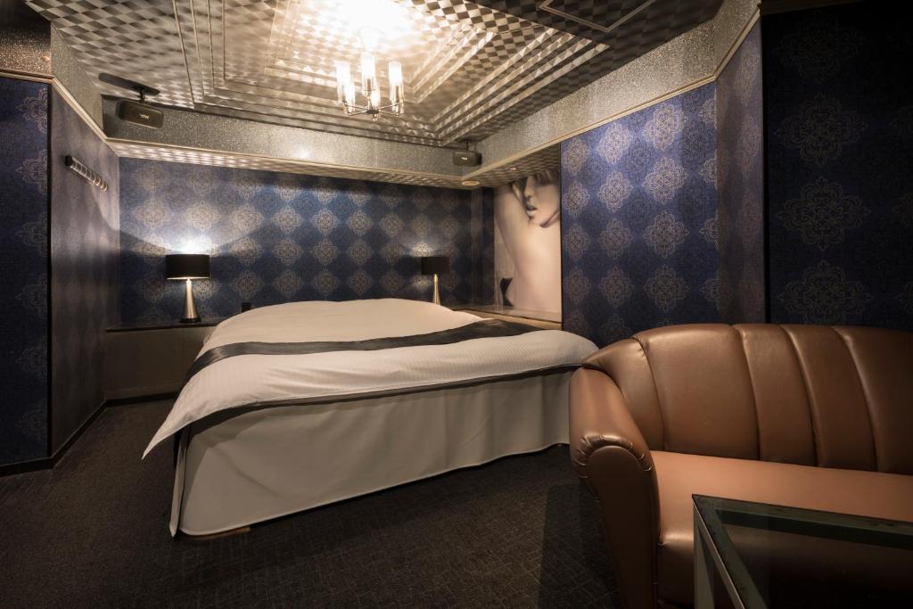 Cette chambre comprend un lit et une chaise. dans l'établissement ホテル ジェムジェム 十三, à Osaka