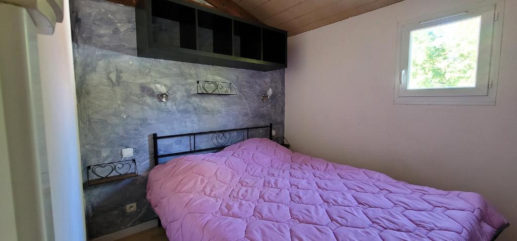 - une chambre avec un lit rose et une fenêtre dans l'établissement Le Verdoyant, à Thenon