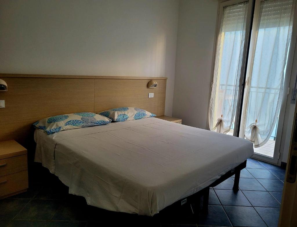 une chambre avec un grand lit et une grande fenêtre dans l'établissement Residence Désirée, à Rimini
