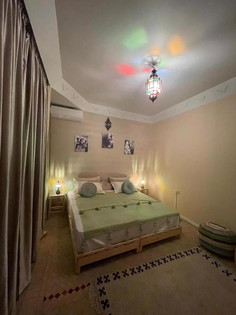 - une chambre avec un lit et un plafond orné d'un lustre dans l'établissement Riad Baroud, à Marrakech