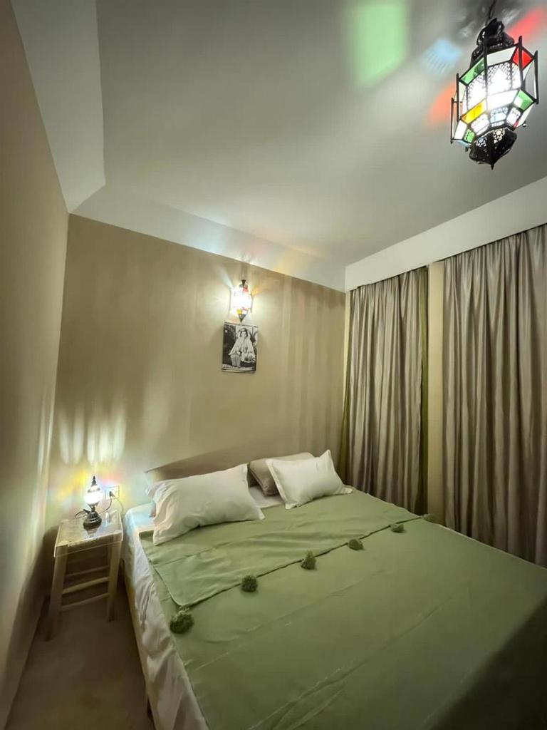 une chambre avec un lit vert avec une lampe et une table dans l'établissement Riad Baroud, à Marrakech